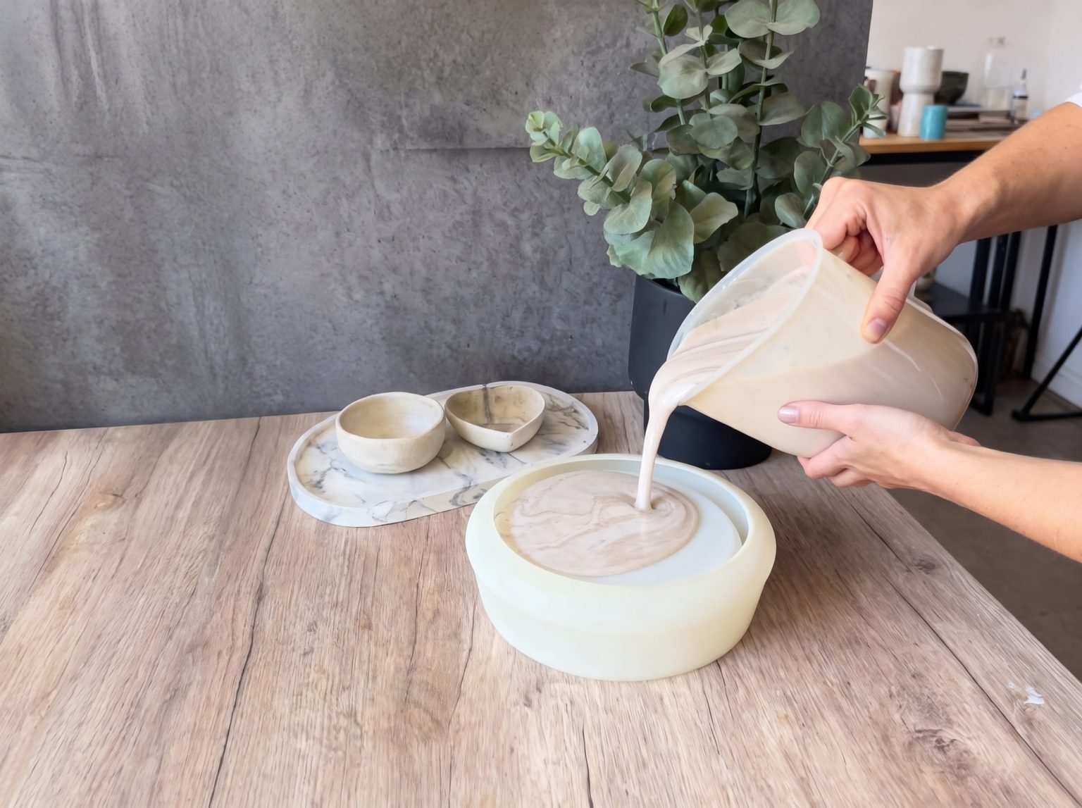 Hands pouring liquid resin into a mould to make a bowl